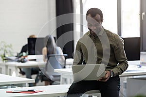 Happy afro american businessman sitting on his desk and typing