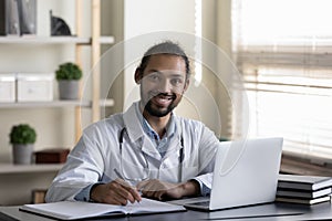Happy Afro American doctor, general practitioner working in hospital office photo