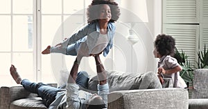 Happy afro american father and kids playing in living room