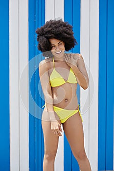 Happy afro american girl in yellow bikini posing on blue white b