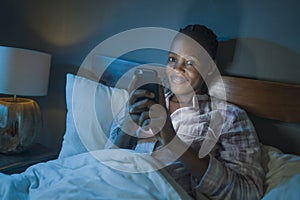 Happy Afro American millennial woman as social media addict - night lifestyle portrait of young beautiful and cool girl texting or