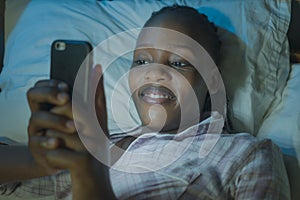 Happy Afro American millennial woman as social media addict - night lifestyle portrait of young beautiful and cool girl texting or