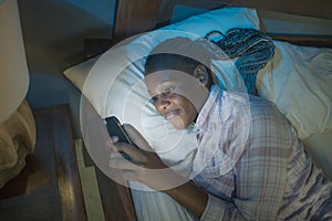 Happy Afro American millennial woman as social media addict - night lifestyle portrait of young beautiful and cool girl texting or