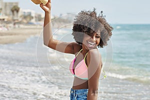 Happy afro american woman raising hand laughing at seaside