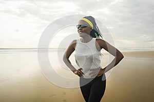 Happy afro American woman running on the beach - young attractive and athletic black girl training outdoors tired after jogging