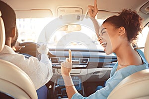 Happy afro couple driving in car and singing song