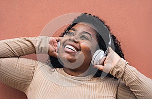 Happy Afro Latin girl having fun listening music with wireless headphones