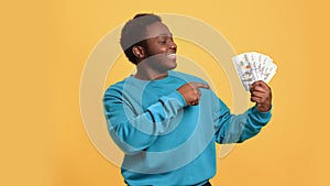 Happy Afro man cash money dollar fan enjoy success lottery win financial abundance isolated orange