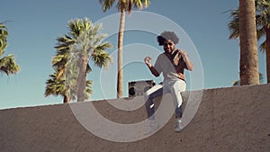 Happy Afro man having fun listening to music with vintage boombox stereo in tropical place during summer vacation