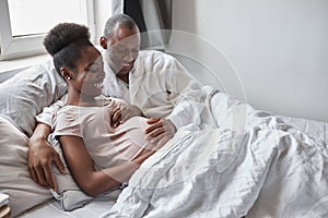 Happy afroamerican married couple lie on bed