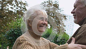 Happy aged people spending time outdoor, mature woman hugging senior man, slowmo