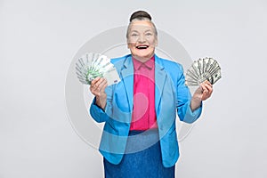 Happy aged woman holding many euro and dollars