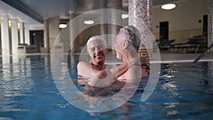 Happy aging couple in swimming pool of spa hotel