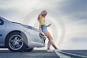 Happy alone young woman traveler on road with car with hand holding mobile phone. Traveler car in summer road trip concept. search