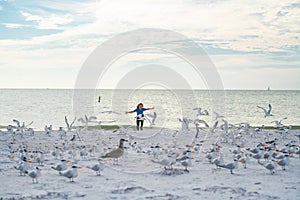 Happy amazed kid running, chasing birds. Little kid boy having fun on Miami beach. Happy cute child running near ocean