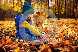 Happy amazed little child, adorable girl in colorful warm clothes enjoying outdoor games in beautiful autumn golden park,