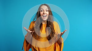 Happy amazed  woman saying yes and rejoices good news on blue background