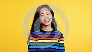 Happy amazed woman saying yes and rejoices good news on yellow background