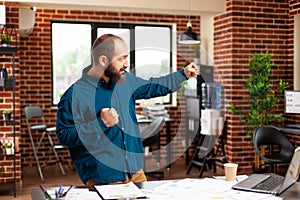 Happy ambitious successful businessman making victory dance in startup office