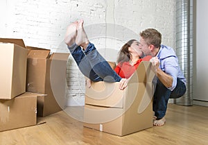 Happy American couple unpacking moving in new house playing with unpacked cardboard boxes