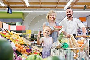 family shopping various fresh fruits in supermarket