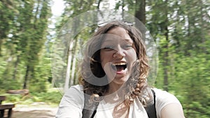 Happy, amused and excited laughing young girl makes video selfie at smartphone camera, spins around during walk in park