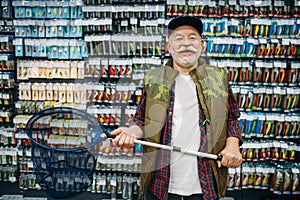 Happy angler holds net in fishing shop