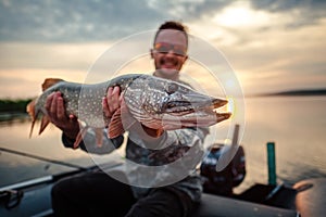 Happy angler holds pike fish