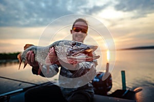 Happy angler holds pike fish