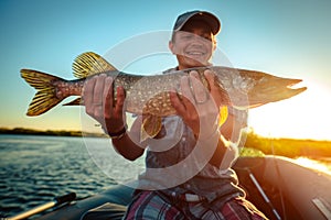 Happy angler holds pike fish