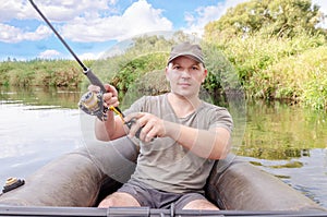 Happy angler sits in a boat on a sunny day