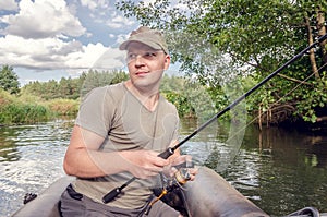 Happy angler sits in a boat on a sunny day