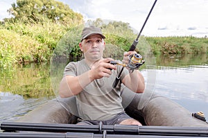 Happy angler sits in a boat on a sunny day