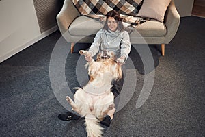 Happy animal is lying down on the floor. Woman is with golden retriever dog at home