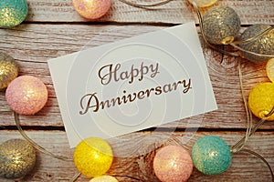 Happy Anniversary card typography text with LED cotton ball on wooden background