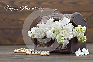 Happy Anniversary card. White lilac flowers in wooden chest