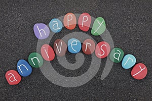 Happy Anniversary text with multicolored sea stones over black volcanic sand