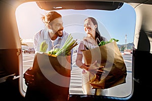 Happy arab couple with bags of groceries by car