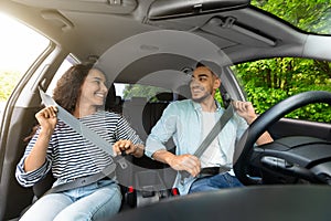 Happy arab couple fastening seat belt, going vacation by auto