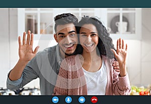 Happy arab couple making video call with laptop in kitchen interior, screenshot