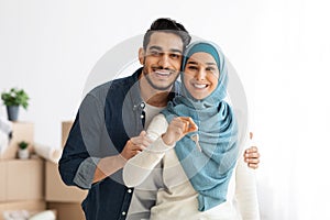 Happy arab family embracing and showing apartment key