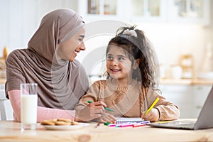 Happy Arab Family Mom And Little Daughter Drawing Together In Kitchen