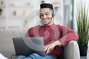 Happy arab guy attending online webinar, using laptop and headset