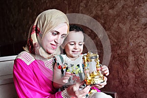 Happy arab muslim mother with her baby girl with ramadan lantern