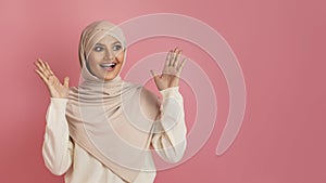 Happy arab muslim woman in hijab spreading hands in excitement