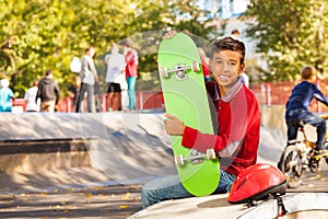 Happy Arabian boy with green skateboard sitting