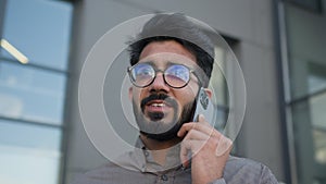 Happy Arabian businessman talk mobile phone in city near business office building smiling Indian muslim man talking