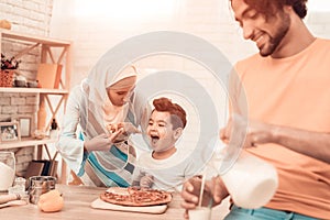 Happy Arabian Family Eating Pizza in Kitchen.