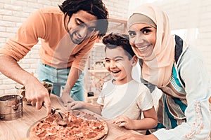 Happy Arabian Family Eating Pizza in Kitchen.
