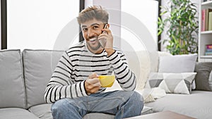 Happy arabian man, enjoying a relaxing breakfast, sitting, coffee cup in hand
